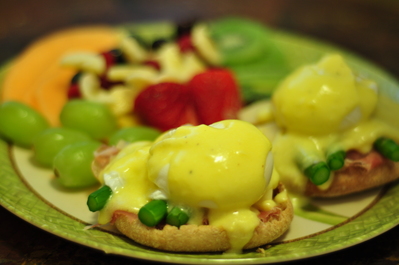 Eggs Benedict with fruit in the background