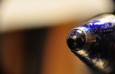 The tip of a ballpoint  pen up close, check out the reflection of the lens in the ball