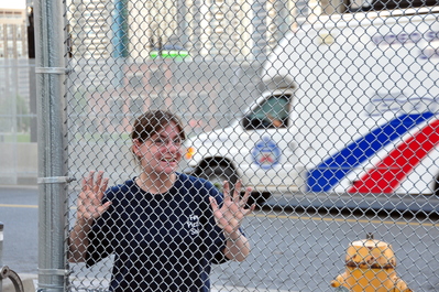 Kim with fence and Police truck