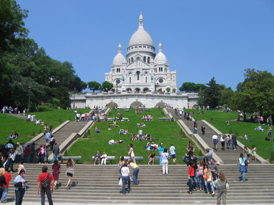 The front of Sacre Coeur basillica and some of the hills with people on them